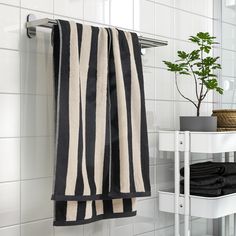 a black and white striped towel hanging on the wall next to a small potted plant