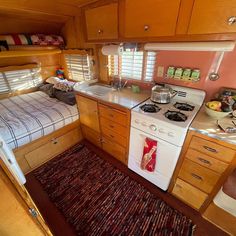 a kitchen area with stove, sink and bed in the back side of a motorhome