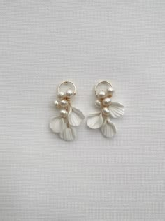 two white flowers with pearls hanging from the end of each earring, on a white background