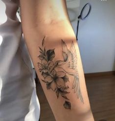 a woman's arm with flowers and birds tattoo on the left side of her arm