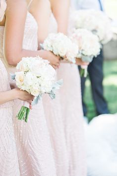 the bridesmaids are holding their bouquets with white flowers in each one's hands