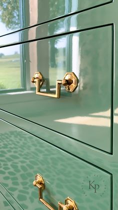 a green dresser with brass handles and knobs