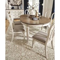 a dining room table with chairs and a rug on the floor in front of it