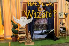 there is a wizard themed stage set up with an owl on the floor and bookshelves