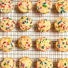 colorful sprinkles on top of cupcakes cooling on a wire rack