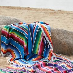 a blanket is laying on the beach next to some rocks