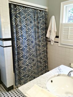 a bathroom with a sink, shower curtain and black and white tile