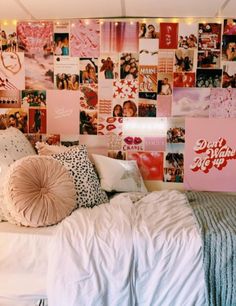 a bed with lots of pillows and pictures on the wall