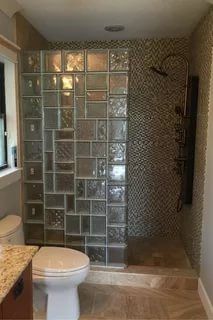 a bathroom with a glass block shower and toilet