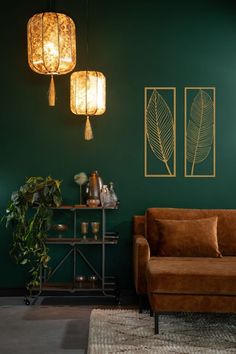 a living room with green walls and two lamps hanging from the ceiling, next to a brown couch