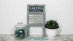 there is a potted plant next to a laundry basket on the counter with a sign above it