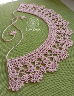 a pink crocheted necklace is laying on a green mat