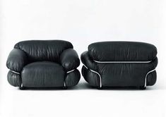 two black leather chairs sitting next to each other on a white surface with one chair facing the other