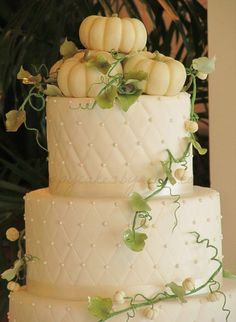 a wedding cake with white frosting and pumpkins on top