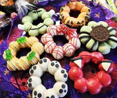 many different types of donuts on a purple cloth covered table with feathers and decorations