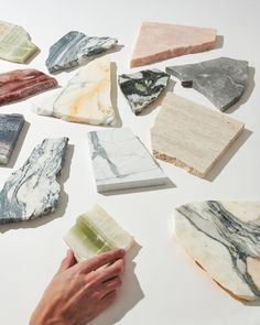 several different types of soaps being held by someone's hand on a white surface