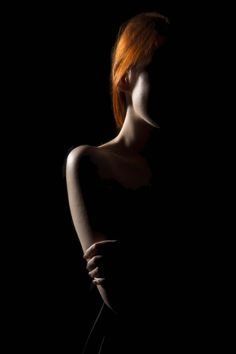 a woman with red hair standing in the dark