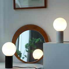 two lamps sitting on top of a table next to a mirror