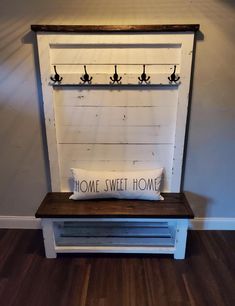 a bench with a pillow that says home sweet home hanging on the wall above it