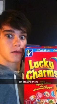 a young man holding up a lucky charms box