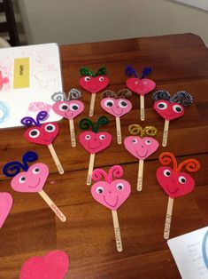 a table topped with lots of paper hearts and eyeballs on top of wooden sticks