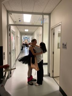 two women hug each other in an empty hallway