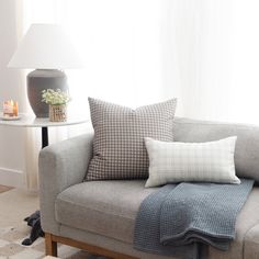 a couch with pillows on it and a lamp next to the window in front of it