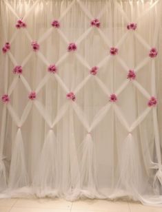 a white curtain with pink flowers hanging on it's side and sheer curtains behind it