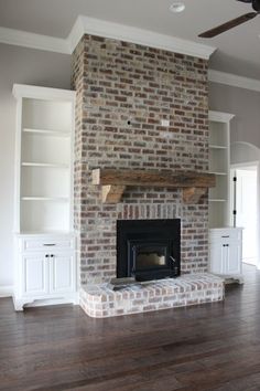 an empty living room with a fireplace and built in bookshelves