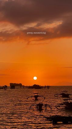 the sun is setting over some boats in the water