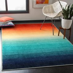 a room with a rug, chair and potted plant