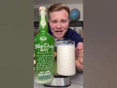 a man is holding up a bottle of blue cheese and a glass of yogurt