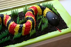 a snake in the grass on top of a green tray with plants and fake eggs