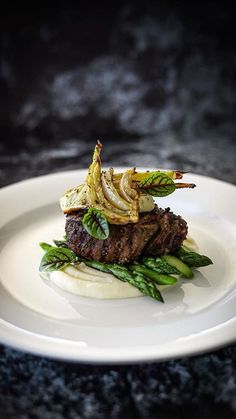 a white plate topped with steak and asparagus on top of a black table