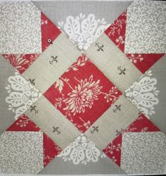 a red and white patchwork quilt on a gray table cloth with an image of a flower