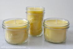 three jars filled with candles sitting on top of a white countertop next to each other