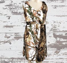 a mannequin wearing a camo print dress on a wooden background with white paint