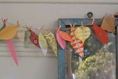 colorful paper hearts are hanging from a clothes line on a window sill in front of a mirror