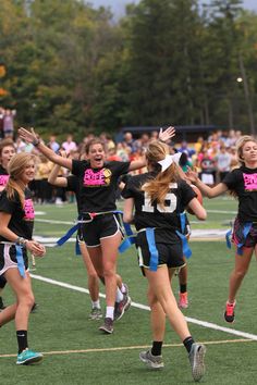 the girls are playing frisbee on the field in front of an excited crowd