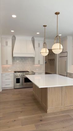 a large kitchen with an island and two lights hanging from it's ceiling over the stove