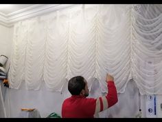 a man is painting the curtains in his room with white paint on the walls and ceiling