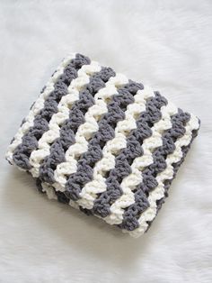 a gray and white crocheted blanket sitting on top of a bed