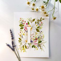 the letter j is surrounded by wildflowers and daisies on a white surface