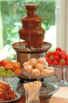 an assortment of desserts and pastries on a table with a fountain in the background