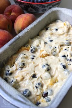 a bowl of blueberries and peaches next to a pan of food on a table