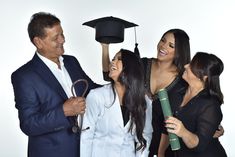 three women and one man are smiling at each other while they hold up their graduation caps