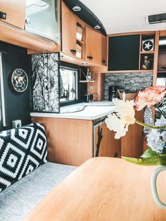 the interior of an rv with wood cabinets and flowers in vases on the table