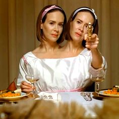 two women sitting at a table with plates of food