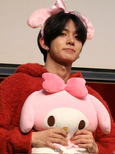 a woman in a pink outfit holding a stuffed animal