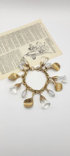 "Gorgeous vintage Coro charm bracelet. Goldtone link chain with clear lucite rock beads, clear confetti lucite oval beads and twisted textured metallic leaf shaped charms. This piece is unmarked but I am 100% positive it was made by Coro. I have seen the exact same piece with the original foil pegasus Coro tag.  In excellent condition with minor wear from age.  Bracelet is 7 3/4\" long. The chain is 8.5mm wide. The largest beads/charms measure around 1 1/4\" long." Rock Vintage, Oval Beads, Gold Charm Bracelet, Beads Charms, Leaf Shapes, Bracelet Jewelry, Gold Charm, Link Chain, Charm Jewelry